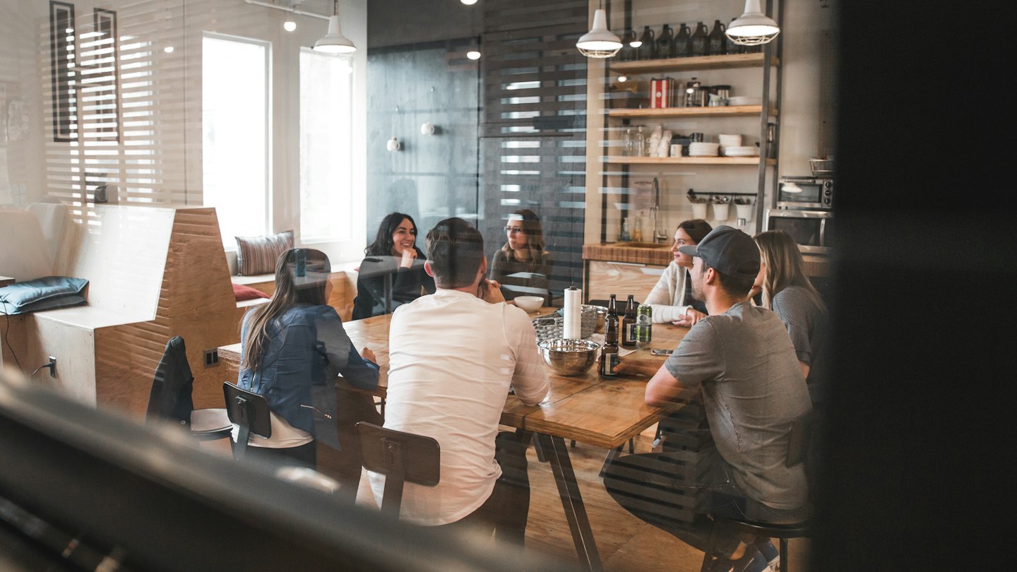 Giovani adulti che collaborano attorno a un tavolo in un luminoso spazio di co-working.